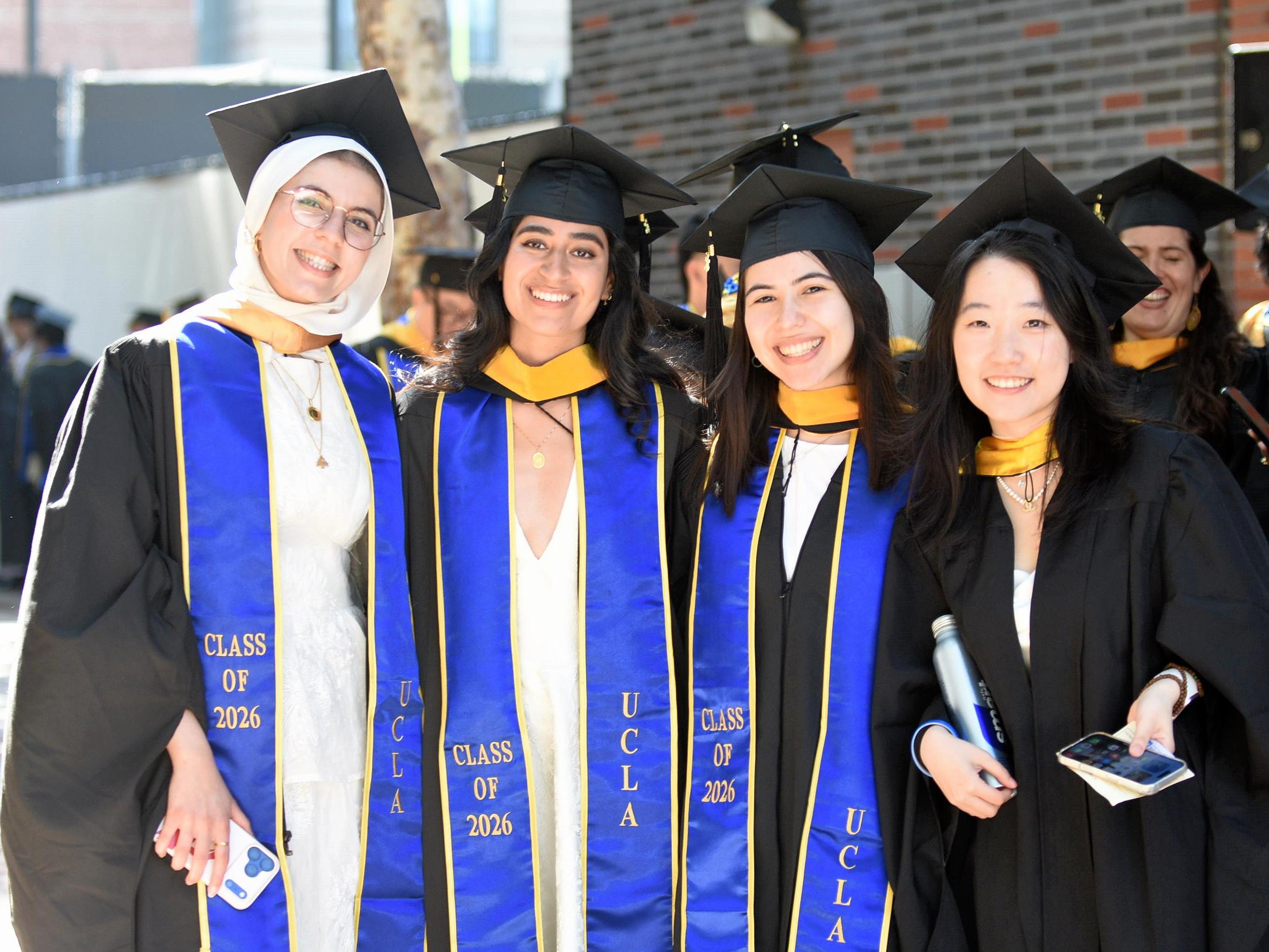 Four UCLA graduates celebrating together in caps and gowns